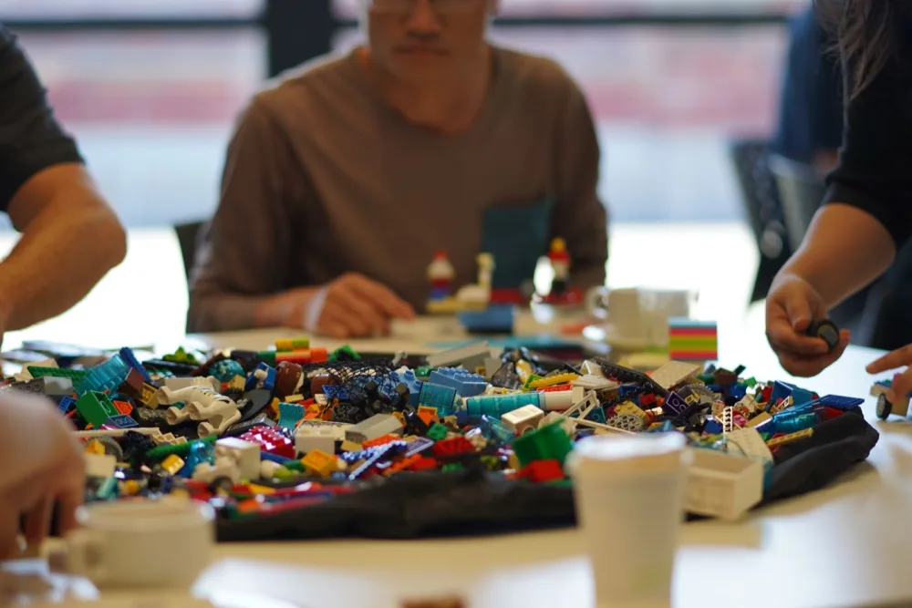 A close-up of loose LEGO bricks spread across the table before a Brick Spark workshop begins