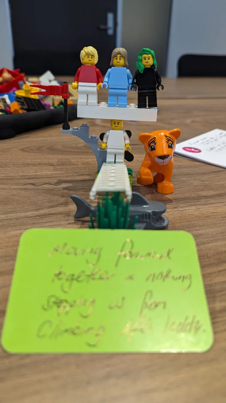 A LEGO Serious Play model with a handwritten sticky note reading Moving forward together and nothing stopping us from climbing life's ladder