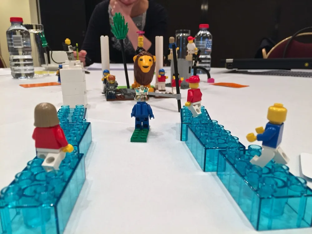 A participant building a LEGO Serious Play model featuring a lion and a crowned minifigure during a Brick Spark workshop
